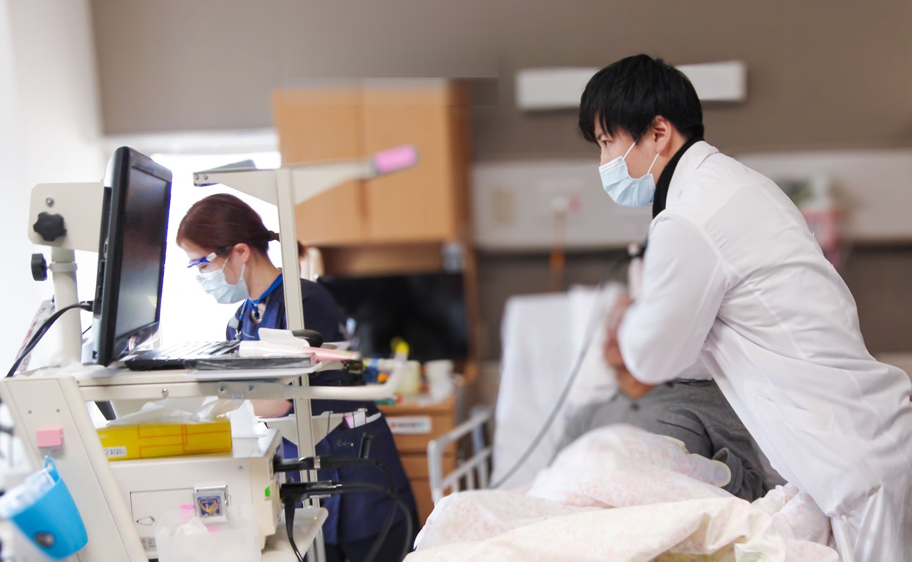 病室で医師と看護師が患者を診察する回診の様子